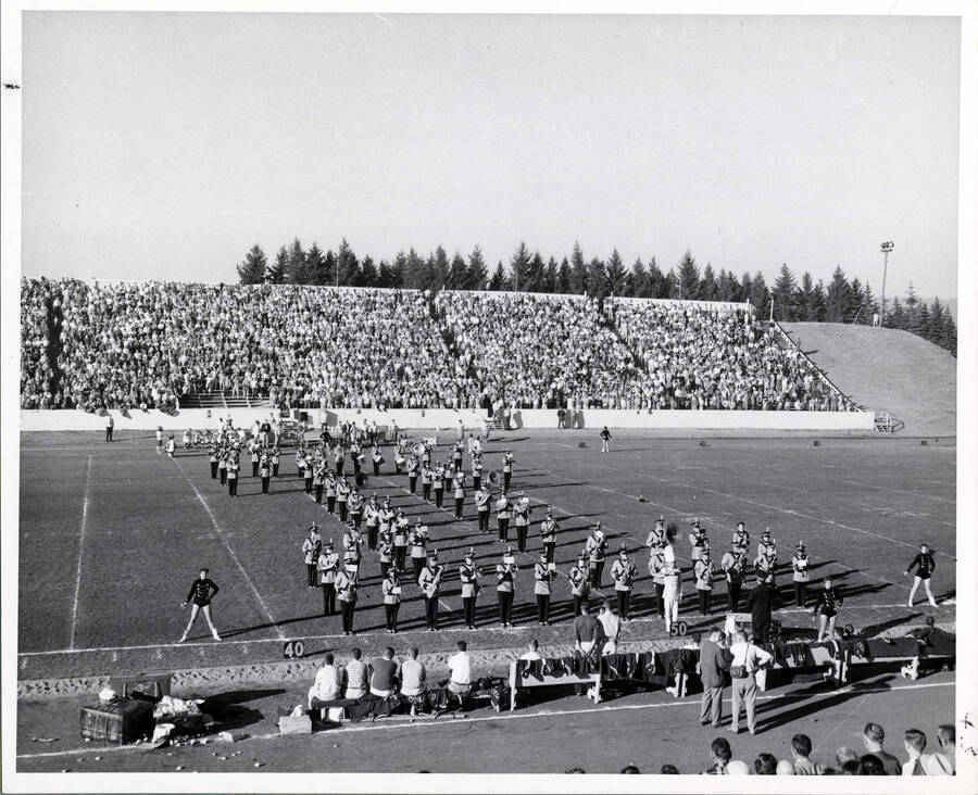 Marching band at football game, standing in the shape of an I. Donor: Publications Department.