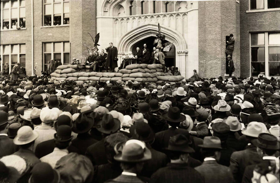 Theodore Roosevelt on platform in front of University of Idaho Administration Building pointing to the crowd assembled for his speech.