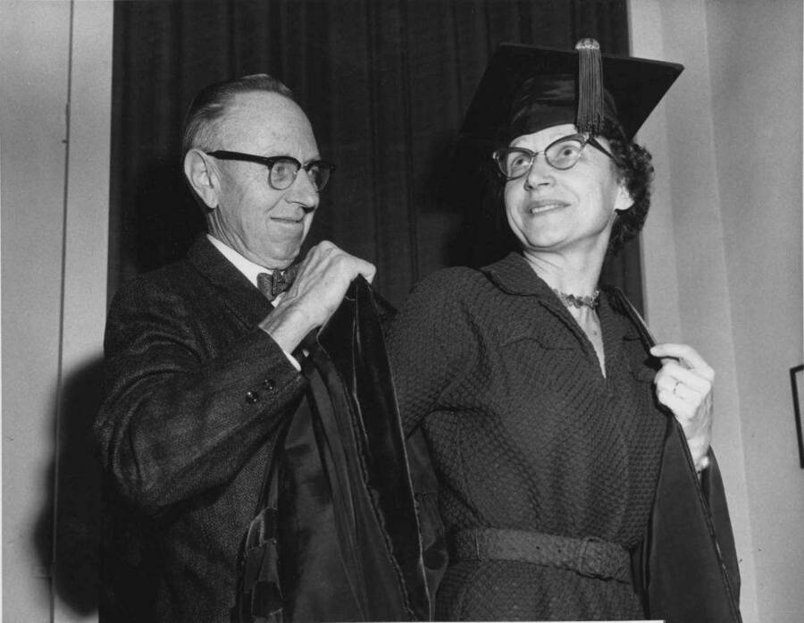 A. R. Aller, the Associate Professor of Botany, helping Florence Aller into her robe. Florence Aller is the recipient of first Doctor of Education degree at the University of Idaho.