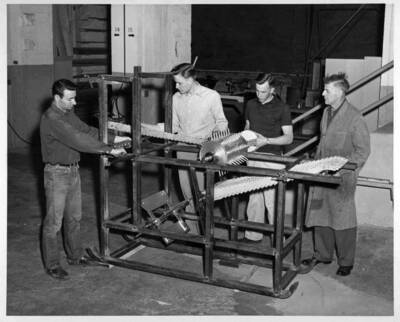 Professor demonstrates a bean tresher to students in the Agricultural Engineering shop buidling.