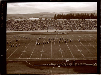 Marching band at football field  in various formations, including the shape of the state of Idaho.