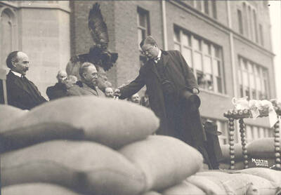 Theodore Roosevelt on platform in front of University of Idaho Administration Building leaning toward Idaho Governor James Hawley. University of Idaho President James MacLean is to the right of Hawley.