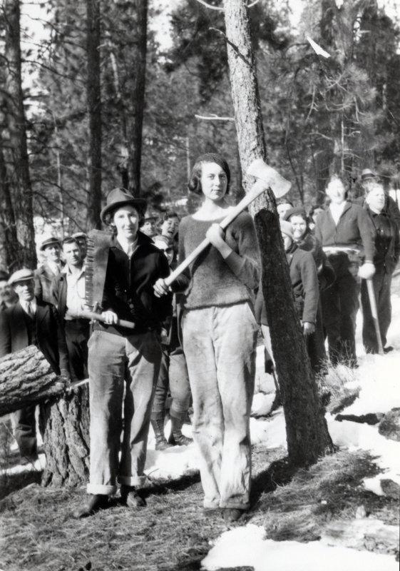 Ruth Turcotte (left) standing with saw and June DeGraff (right) with axe, in Rose Lake, Idaho. A crowd of spectators are in the background. Courtesy of Ruth Hoerschger Turcotte.