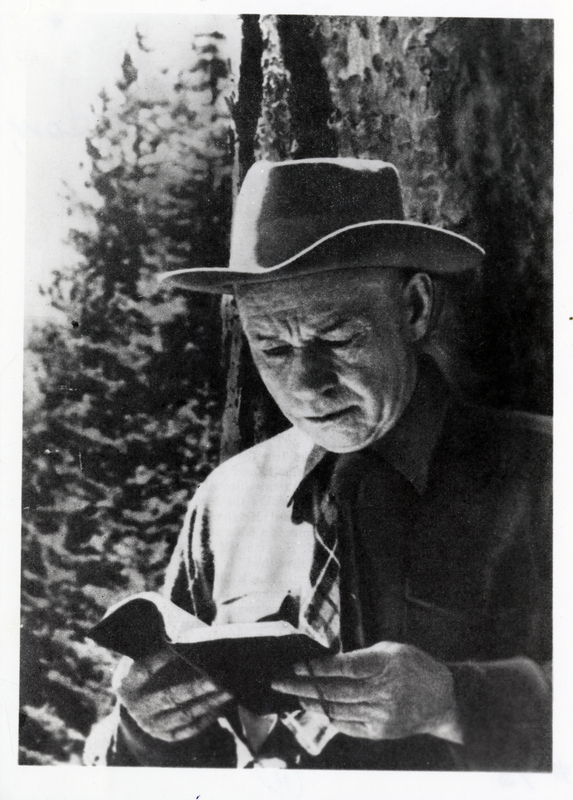 A picture of Reverend 'Dick' Richard E. Ferrell reading a book outdoors. Lumberjack missionary of the Coeur d'Alenes. Dick was also formerly a blacksmith and prize fighter. Courtesy of Mrs. Richard E. Ferrell.