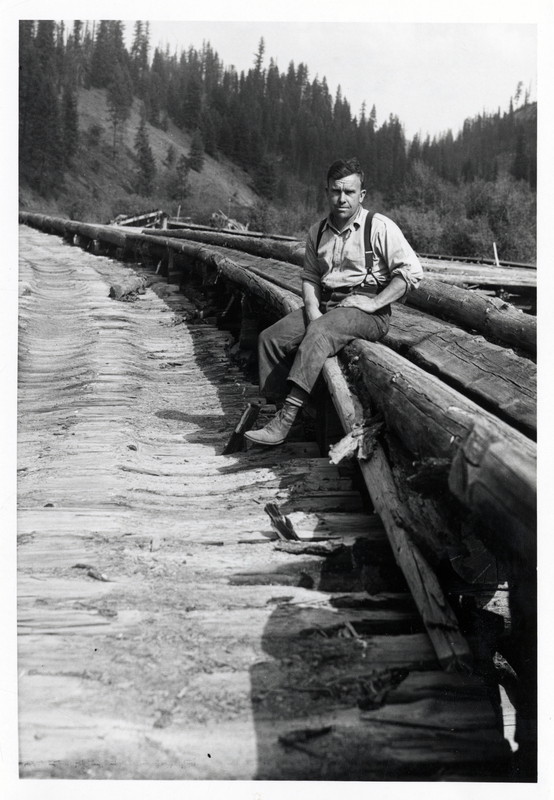 A picture of Neil Fulleron sitting at the Mica Creek Trailing Chute. This is where the chute landing met up with the Mica Creek Flume. Beginning of Flume can be seen in the background. Saint Joe National Forest.