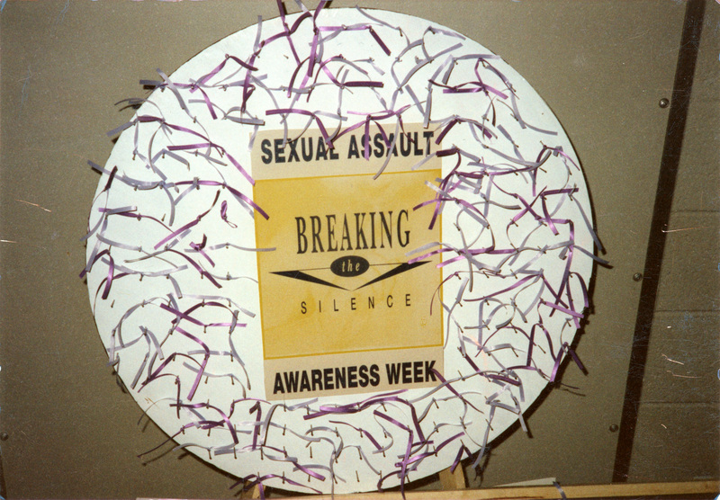 A poster which reads "Sexual Assault: Breaking the Silence" in a wreath covered in ribbon.