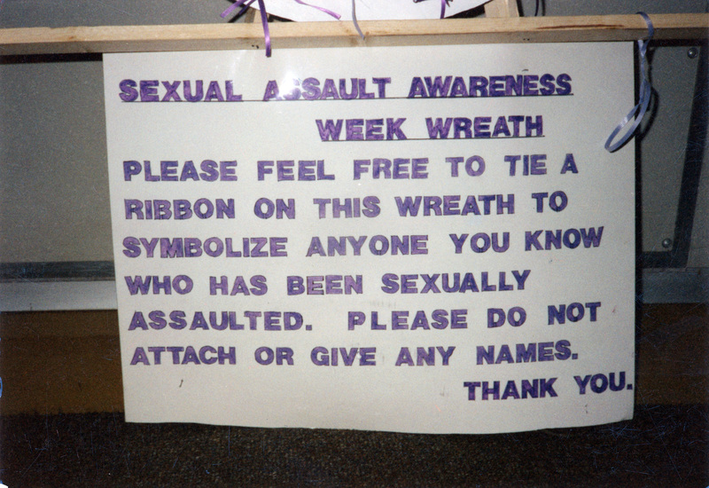 Sexual Assault Awareness Week Poster describing the purpose of the wreath. Transcript: "Sexual Assault Awareness Week Wreath. Please feel free to tie a ribbon on this wreath to symbolize anyone you know who has been sexually assaulted. Please do not attach or give any names. Thank you."