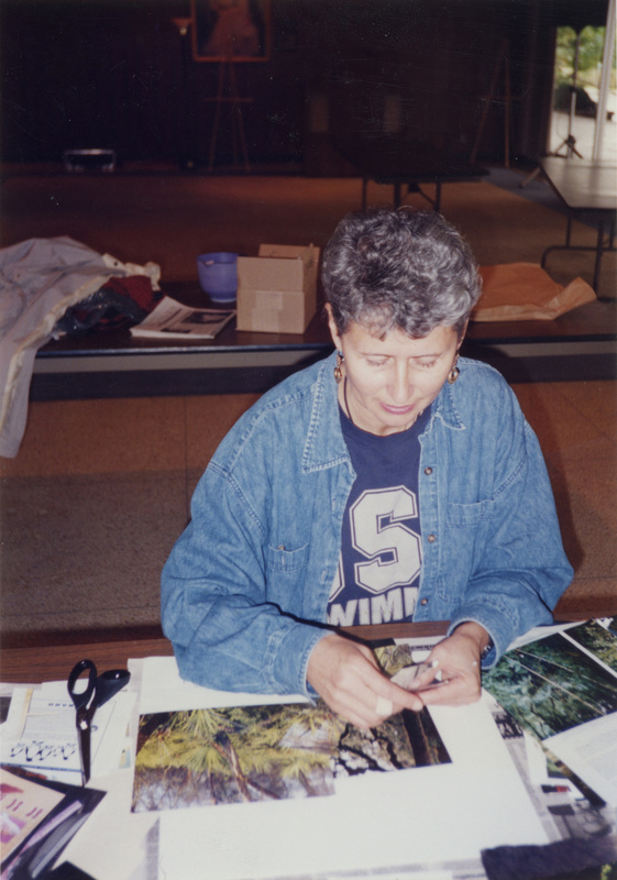 Debbie McLaughlin working on a collage. There are cut-out photos of woodland scenes near her project.