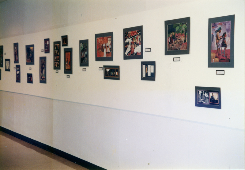 A shot of an art gallery of matted artwork hung on a white wall.
