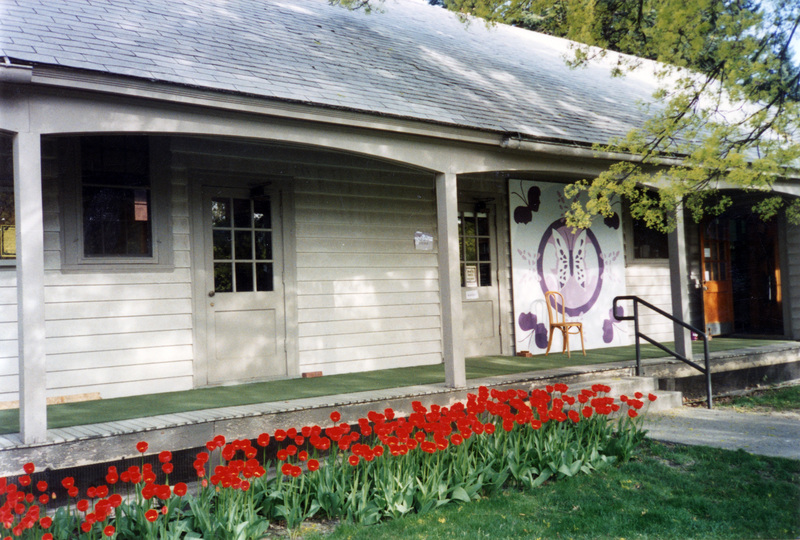 A shot of the exterior of the Women's Center building. Red flowers grow in front of the porch.