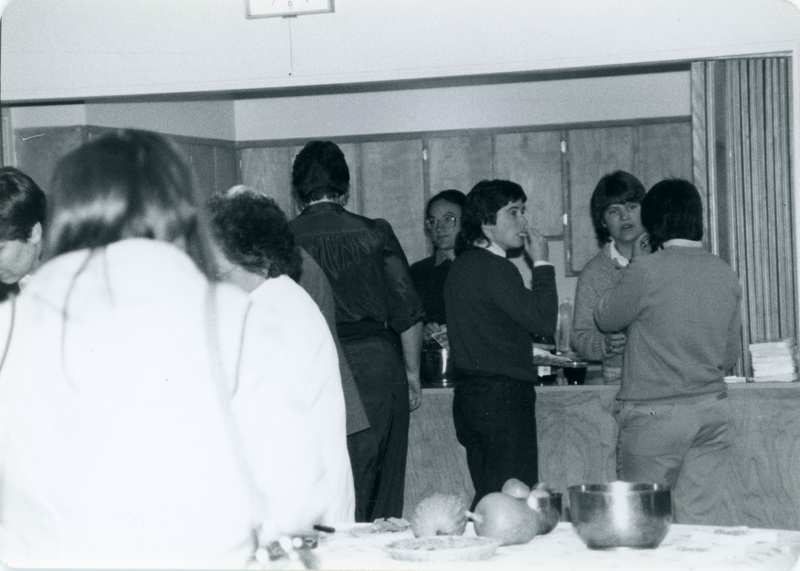 Mary Emary, assistant to Corky Bush, in a crowd of people at an event. A caption stated "Mary is now at LCSC." There is an unidentified woman in glasses in the background.