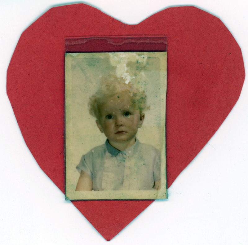 A handmade ornament with a photograph of a young child in the middle.