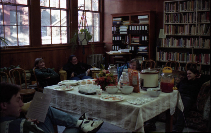 People sitting around a table filled with food and drinks in the Women's Center during a celebration.