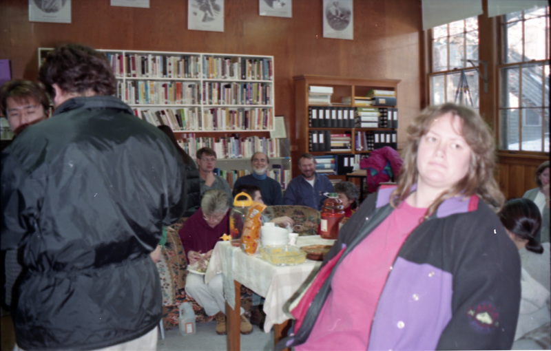 People sitting in the Women's Center eating food. Some people stand in the foreground.