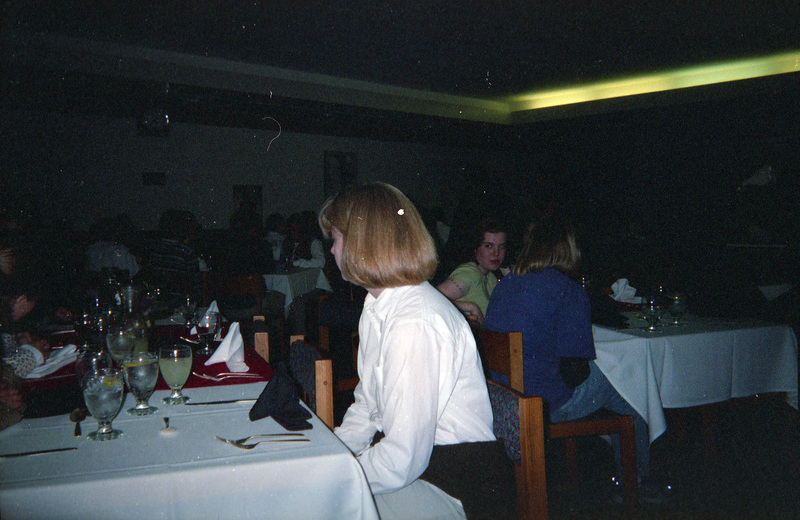 People sitting at tables set to eat. The room is dimly lit.