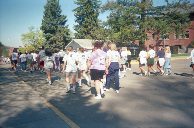 People walking in a race on campus. The walkers are wearing bib numbers.