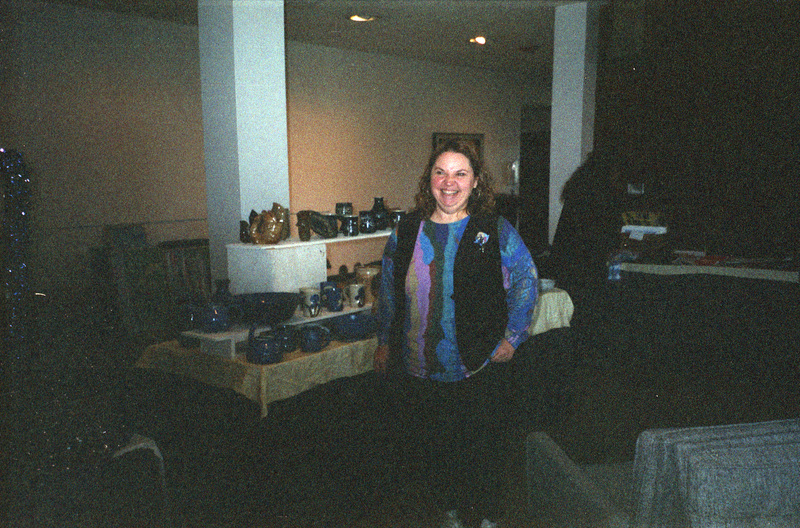 Jeanne Wood stands in front of a booth layered with pottery.