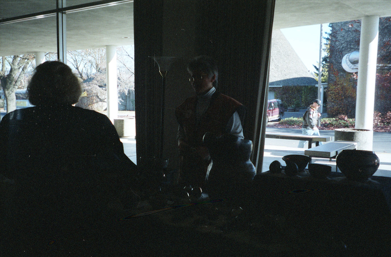 Two people standing near a booth at the first WomensWorks Arts and Crafts Fair in 1995 at the old SUB (now the Bruce M. Pitman Center). Rebecca Rod is standing behind the table.