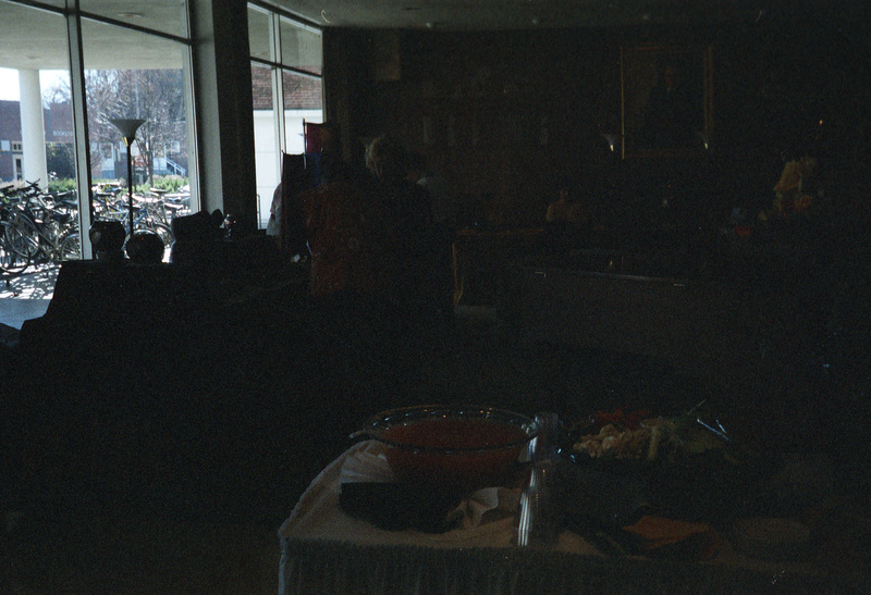 A dimly lit photo. There appears to be a table with food in the foreground and a booth with pottery on the left.