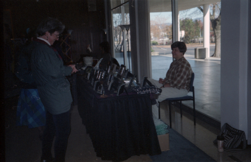 A person looking at items at a booth. The items appear to be framed images of some kind.