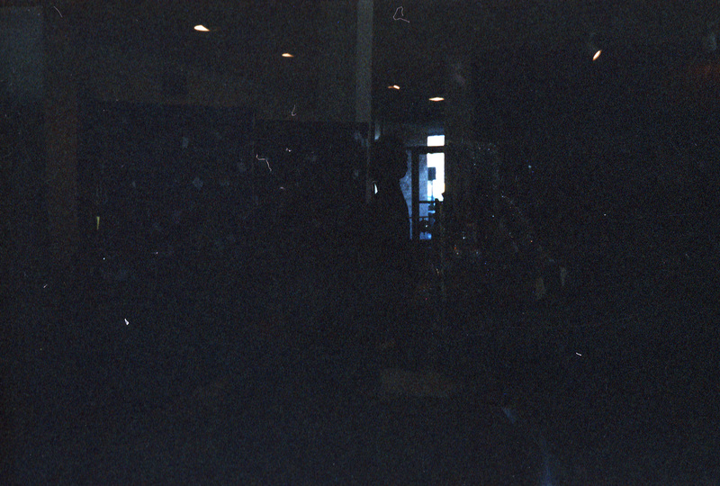 A dimly lit photo. There appears to be a person standing near several booths.
