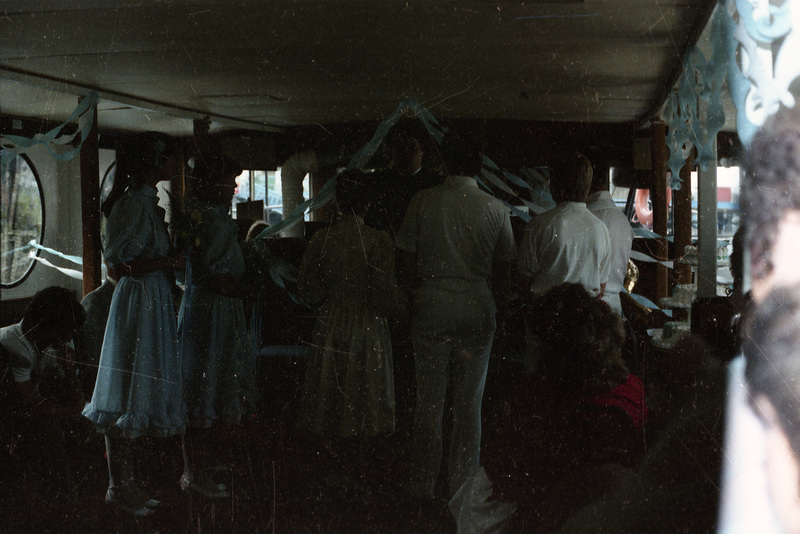 A group of people (possibly the wedding party) standing near each other. The event appears to be a wedding, with bridesmaids on the left and groomsmen on the right, and the bride and groom in the center.