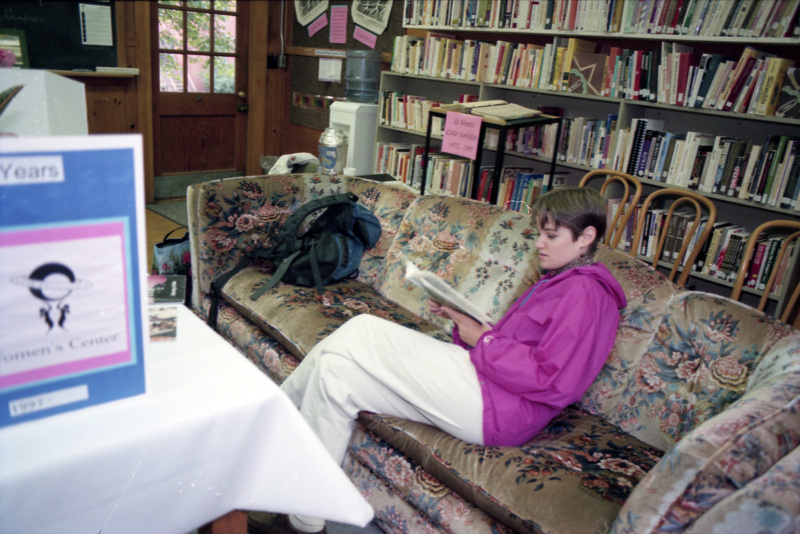 A person reading something while sitting on a couch in the Women's Center.