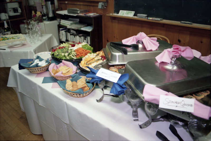 A photo of a spread of food, including vegetables, crackers, cheeses, quiche, and cake.