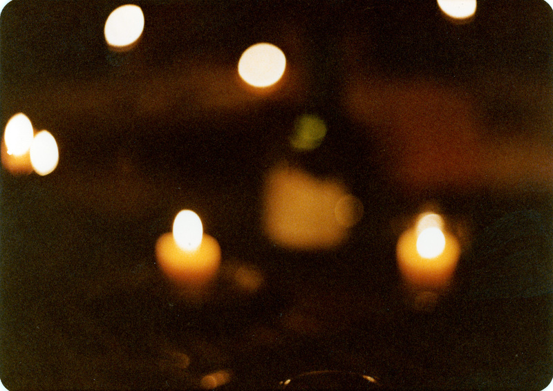 Photo from a recreation of Judy Chicago's The Dinner Party, held in St. Augie's. The image is out of focus and consists of several bright spots. 