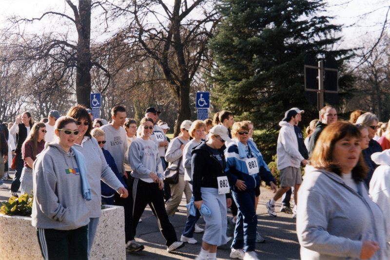 A group of people wearing race numbers walking past the camera.