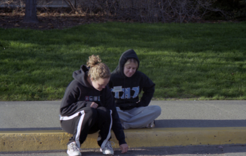 Two people sitting on a curb.