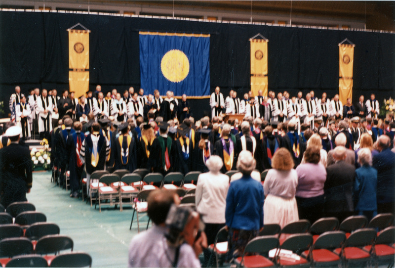Scene during Elisabeth Zinser's inauguration. Zinser was the first female president of the University of Idaho. Everyone on stage and in the audience stand.