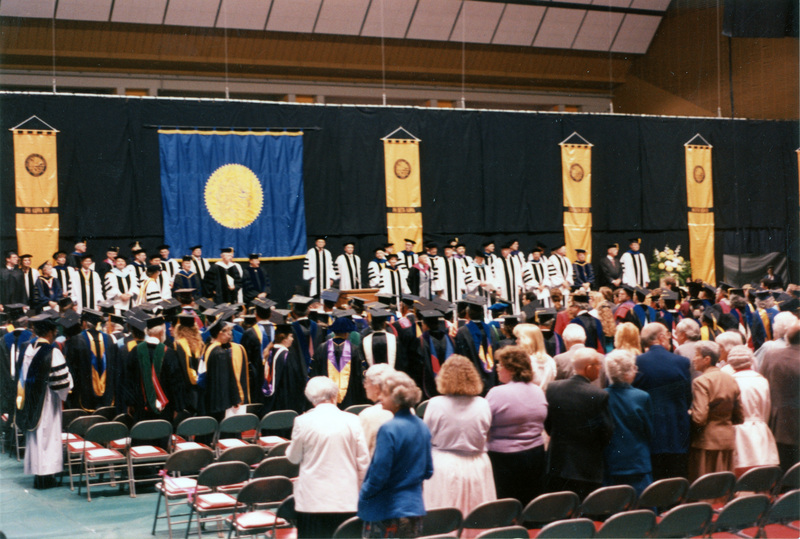 Scene during Elizabeth Zinser's inauguration. Zinser was the first female president of the University of Idaho. Everyone on stage and in the audience stand.
