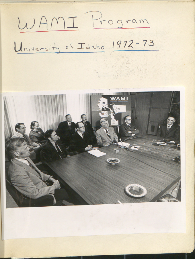 A black and white photograph showing a group of individuals seated around a conference table at the University of Idaho.